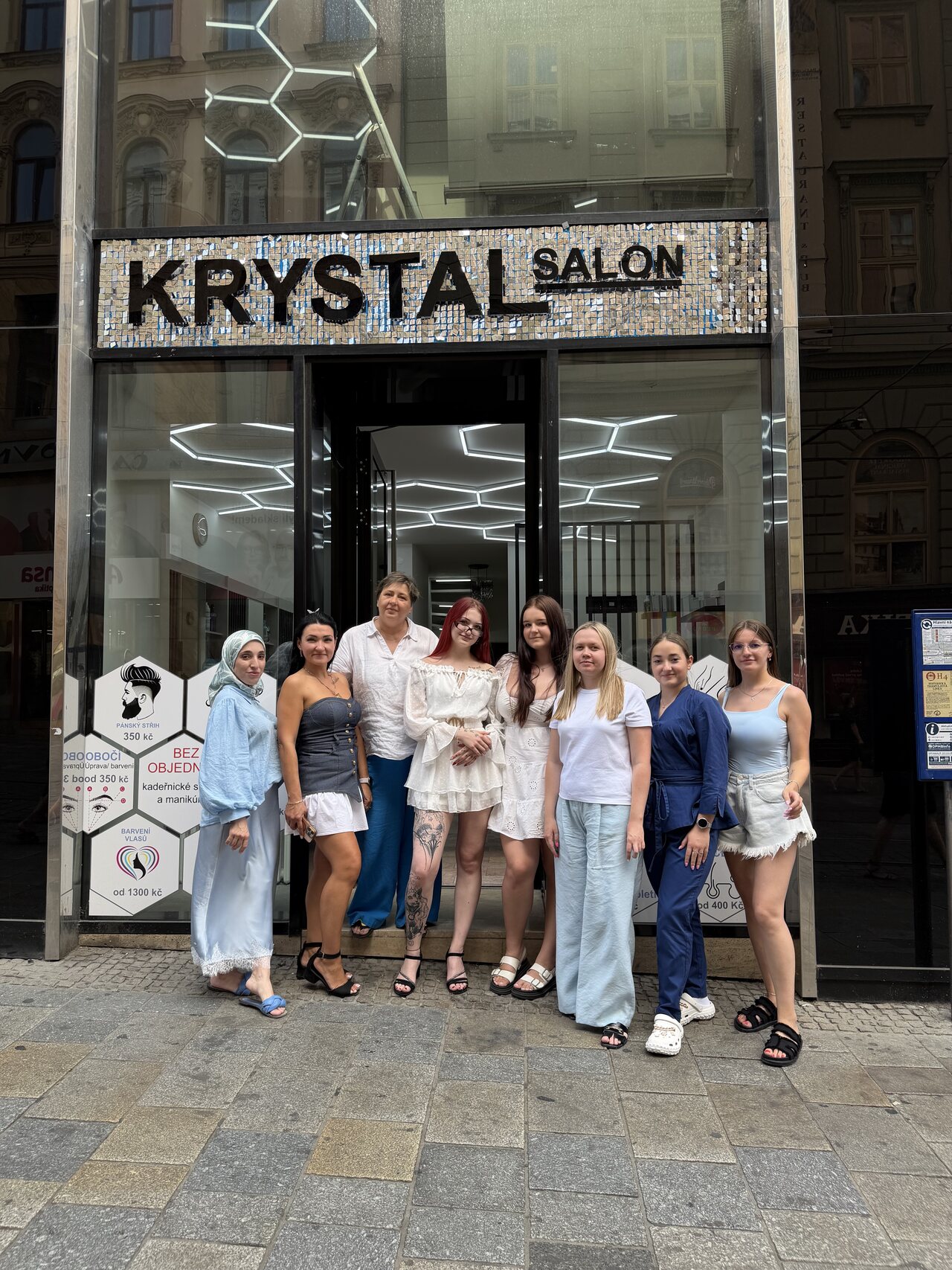 Tým Krystal salonu před výlohou s třpytivým nápisem KRYSTAL SALON na Masarykově ulici v Brně.